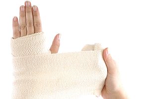 Woman wrapping her hand with a bandage on a white background